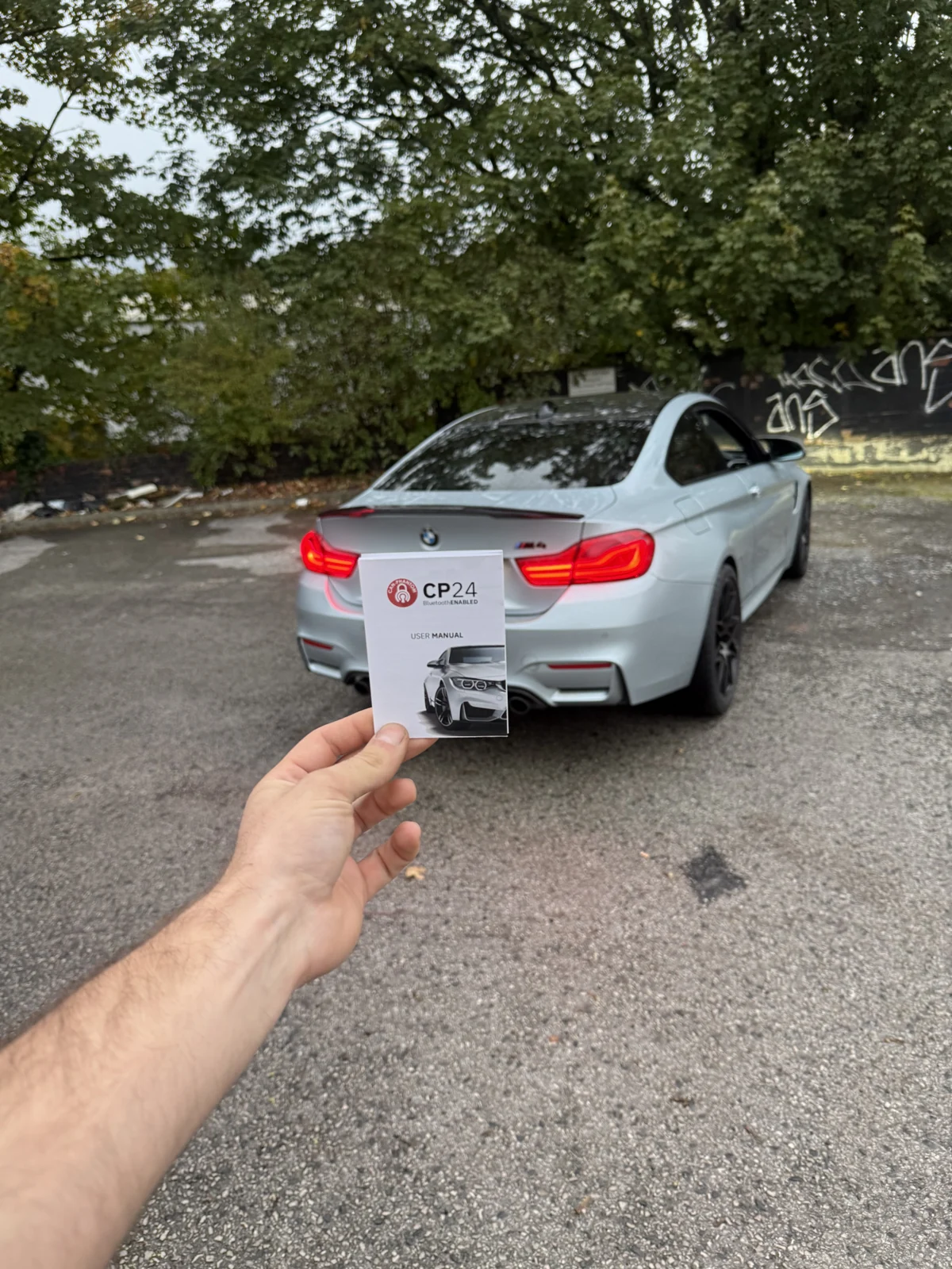 Rear view of the same silver BMW, with a CP24 booklet in the foreground